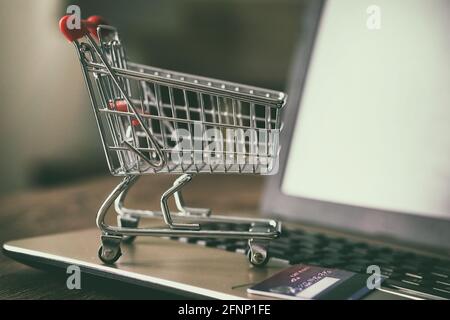 Piccolo carrello di shopping sul computer portatile concetto di pagamento online carta di credito ecommerce consegna a domicilio Foto Stock