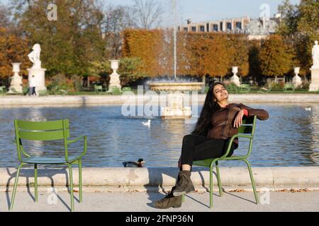 Giovane donna indiana seduta su una sedia in un parco a Parigi, Francia Foto Stock
