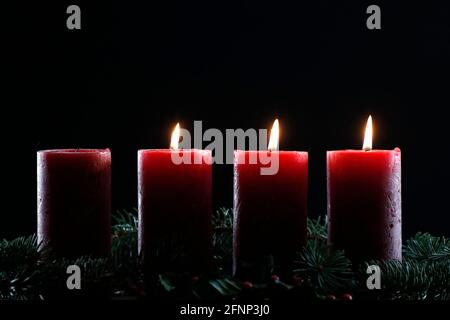 Corona o corona dell'avvento naturale con tre candele rosse brucianti. Composizione di Natale. Francia. Foto Stock