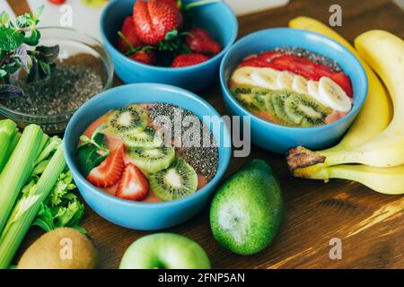 Sul tavolo ci sono tazze di frullati freschi e succulenti, frutta e semi. Foto Stock