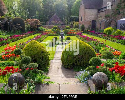 Chenies Manor Sunken giardino nel tardo pomeriggio luce, di fronte a ovest. Il vecchio Padiglione restaurato uno sfondo di tulipani colorati di arancio, rosso e viola. Foto Stock