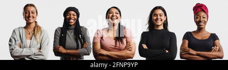 Gruppo di donne multietniche su sfondo bianco. Donne felici di etnia diversa in piedi insieme con le armi incrociate. Foto Stock
