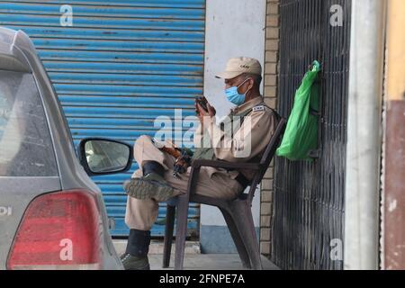 India. 18 maggio 2021. Un soldato paramilitare usa il suo telefono cellulare mentre si siede su una sedia durante il blocco Covid-19 a Srinagar, indiano amministrato Kashmir il 18 maggio 2021. (Foto di Najmus Saqib/Sipa USA) Credit: Sipa USA/Alamy Live News Foto Stock