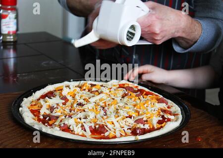 Primo piano di donna e bambino piccolo che fa la pizza fatta in casa. Mani solo nel telaio. Foto Stock