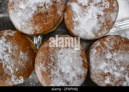 Ciambelle riempite di cioccolato o gelatina cosparse di zucchero in polvere Foto Stock