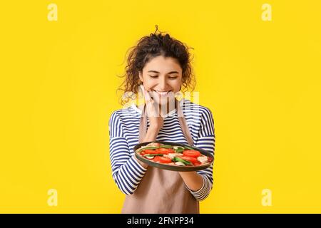 Felice giovane donna con gustosa pizza su sfondo colorato Foto Stock