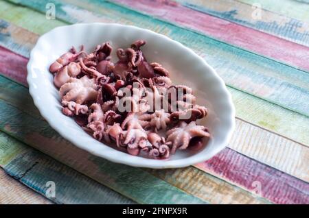 Piccoli polpi su un piatto su un legno colorato background.Seafood sano cibo foto. Foto Stock