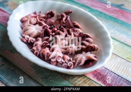 Piccoli polpi su un piatto su un legno colorato background.Seafood sano cibo foto. Foto Stock