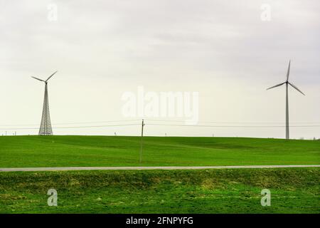 Due turbine eoliche ruotano intorno generando energia nel mezzo di un campo di grano. Parchi eolici, stanno diventando una fonte sempre più importante di Foto Stock