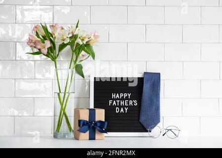 Concetto di giorno dei Padri felici. Composizione festiva con confezione regalo carta artigianale avvolta con nastro blu, cartellone con testo Happy Father's Day, cravatta, Foto Stock