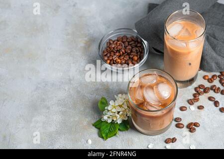 Caffè ghiacciato su sfondo grigio con spazio per la copia. Due bicchieri con una rinfrescante bevanda lattiginosa al caffè. Foto Stock