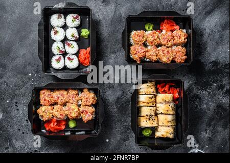I panini di sushi nel pacchetto di consegna, ordinati nel ristorante di sushi take-out. Sfondo nero. Vista dall'alto Foto Stock