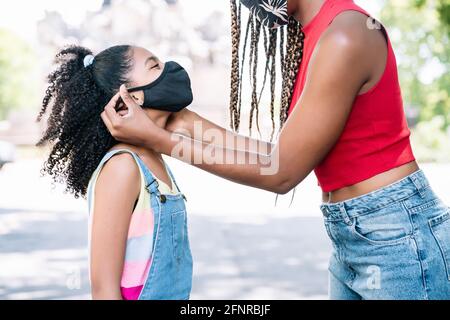 Madre che mette una maschera di faccia su sua figlia. Foto Stock