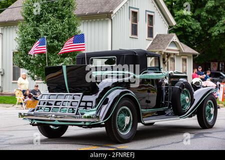 Le bandiere americane sventolano dalla sede rumble di un roadster antico di Auburn 1931 mentre passa attraverso Auburn, Indiana durante la parata di festival di ACD 2019. Foto Stock