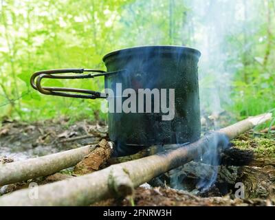 Cucina campo. Cucina sul fuoco durante l'escursione. Pentola appesa al fuoco Foto Stock