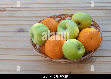 Arance e mele in un cesto su sfondo di legno Foto Stock