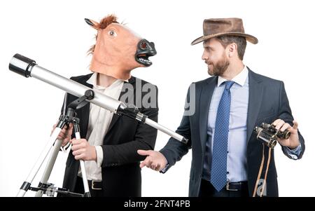 Uomo d'affari in testa a cavallo maschera tenere telescopio e uomo cowboy con binocolo, visione d'affari Foto Stock