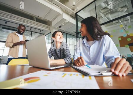 Due giovani donne che si siedono insieme alla scrivania dell'ufficio Foto Stock