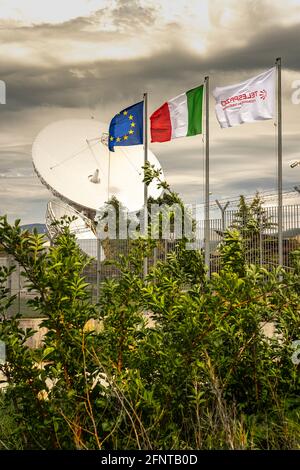 Centro spaziale Telespazio a Fucino. Antenna parabolica per i satelliti in orbita e i servizi di telecomunicazione.Bandiere d'Europa,Italia e Telespazio. Foto Stock