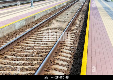 La ferrovia segue le riprese urbane. Linea leader view.Iron rusty treno dettaglio ferroviario su pietre scure ferrovia Foto Stock