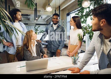 Un team di colleghi diversi in un ufficio moderno discutono il loro progetto insieme Foto Stock