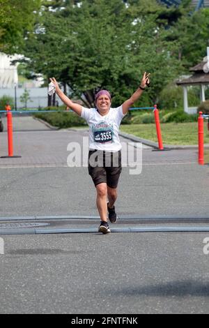 Una giovane donna si è giubilata mentre si avvicina al traguardo della mezza maratona delle regine di NYCRuns nel Flushing Meadows Corona Park a New York City. Foto Stock