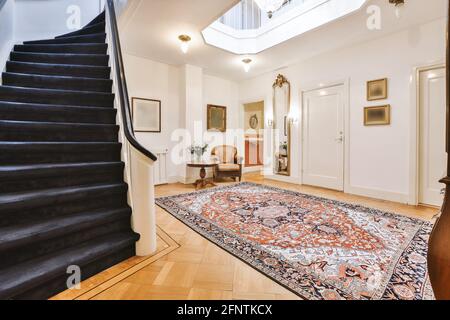 Moquette ornamentale posta sul pavimento vicino alla scalinata nel corridoio vintage di casa elegante Foto Stock