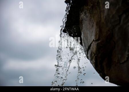 cascata contro il cielo. l'acqua in caduta è congelata nella foto. colpo fresco di acqua spruzzi. Fermati al telaio di una piccola cascata in un parco. Foto Stock