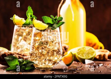 Cocktail alcolico di zenzero con foglie di birra, lime, limone e menta in glassa su tavolo di legno Foto Stock