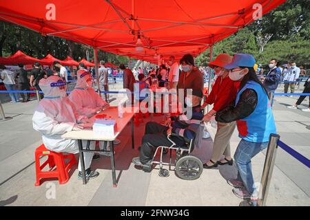 (210519) -- SHENYANG, 19 maggio 2021 (Xinhua) -- UN volontario aiuta un uomo in sedia a rotelle a ricevere test di acido nucleico in un sito di test nel distretto di Heping, Shenyang, provincia di Liaoning della Cina nordorientale, 19 maggio 2021. Shenyang, capitale della provincia di Liaoning della Cina nordorientale, ha ampliato la portata dei test sugli acidi nucleici a seguito di nuovi casi di COVID-19, ha detto le autorità sanitarie locali. Martedì pomeriggio Shenyang ha lanciato test sugli acidi nucleici per i residenti di più aree nei quattro distretti dove finora erano stati segnalati un totale di quattro casi COVID-19 trasmessi localmente. Il test Foto Stock