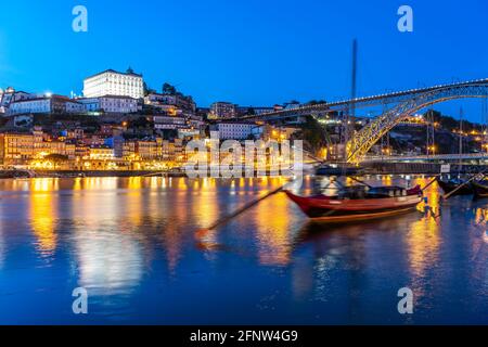 Blick über die traditionellen Rabelo Boote am Douro Ufer in Vila Nova de Gaia auf die Altstadt von Porto und Die Brücke Ponte Dom Luís i in der Abend Foto Stock