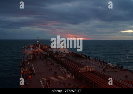 nave cisterna e nave di rifornimento all'ancoraggio sotto le luci del tramonto Foto Stock