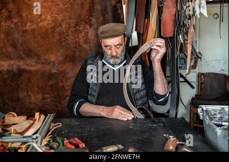 Ritratto di artigiano senior che lavora la pelle nella sua officina. Foto Stock