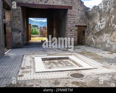 Atrio quadrato con impianto centrale. Il pavimento dell'atrio è costituito da lava frantumata decorata con piccoli trucioli di marmo bianco. Casa del frutteto - Sito archeologico di Pompei, Italia Foto Stock