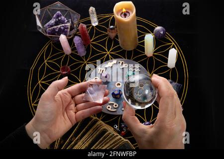 Fortune Telling Table con oggetti esoterici e la mano che tiene la palla di cristallo. Foto Stock