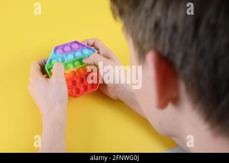 Teenger che gioca con il popolare silicone colorato anti-stress pop it giocattolo esagonale. Primo piano. Foto Stock