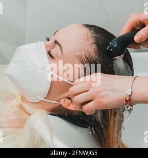 Sciacquare i capelli dopo lo shampoo, cura dei capelli nel barbiere, visitare il parrucchiere durante la quarantena. Nuovo Foto Stock