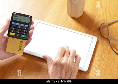 Mani di donna anziana con un tablet pc e un generatore di codice di conferma per accedere al conto bancario, schermo vuoto, mockup. Foto Stock