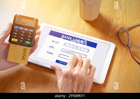 Mani di donna anziana con un computer tablet e un generatore di codici di conferma per accedere online al conto bancario. Foto Stock