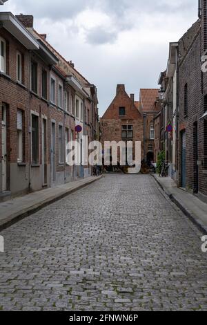 Bruges, Belgio - 12 maggio 2021: Pittoreschi edifici storici in mattoni tipici del centro storico di Bruges con un cavallo e una carrozza nel backgro Foto Stock