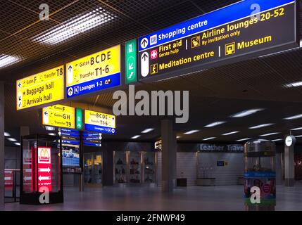 Cartelli informativi e cartelli segnaletici nella sala dell'aeroporto internazionale Schiphol di Amsterdam. Indicazioni per cancelli, bagagli e sale di arrivo Foto Stock