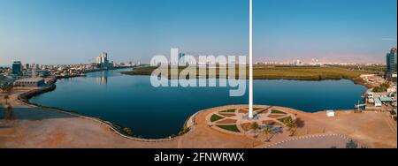 Bandiera nazionale degli Emirati Arabi Uniti e Ras al Khaimah emirano Il punto di riferimento e lo skyline aereo degli Emirati Arabi Uniti del nord vista sopra le mangrovie an Foto Stock