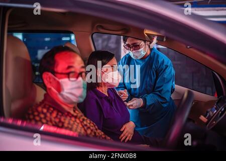 Bogor, Indonesia. 17 Marzo 2021. Un operatore medico somministra una dose di vaccino Sinovac COVID-19 a una donna anziana in un'auto in un sito di vaccinazione drive-thru COVID-19. Il governo indonesiano ha aperto un drive attraverso COVID-19 Servizio di vaccinazione per le persone anziane a Bogor Credit: SOPA Images Limited/Alamy Live News Foto Stock