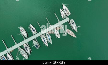 Vista aerea dall'alto di molti yacht bianchi e barche a vela ormeggiate in marina su un'acqua turchese, stagione primaverile. Foto Stock