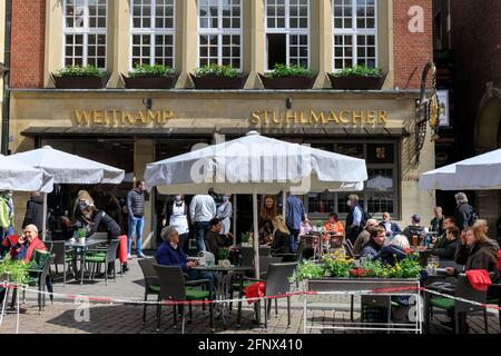 Münster, NRW, Germania. 19 maggio 2021. La gente ama mangiare e bere all'aperto nei caffè, nei bar e nei ristoranti del centro storico di Münster. L'ospitalità all'aperto, compresi caffè e ristoranti, è ora autorizzata ad aprire in Germania, a seguito di un'incidenza per 100.000 persone che rimane al di sotto di 100 per almeno 5 giorni di fila, in singole città o consigli. La città di Münster, di medie dimensioni e relativamente ricca, ha registrato tassi di incidenza relativamente bassi in tutta la pandemia e, attualmente a 16.5/100.000, si colloca ben al di sotto del tasso di incidenza medio tedesco di 72. 8, Credit: Imageplotter/Alamy Live News Foto Stock