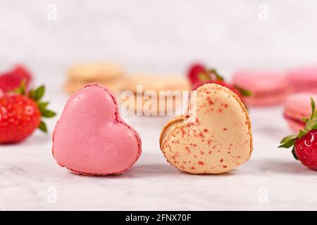 Due dolcetti di macaron francesi a forma di cuore beige e rosa Foto Stock