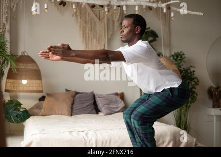 Giovane africano che pratica yoga all'interno in uno spazio di ritiro Posizione sedia in corso o Utkatasana Foto Stock
