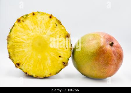 Una fetta intera di mango e di ananas a spicchi di bianco sfondo Foto Stock