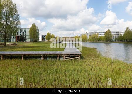 Eindhoven, Paesi Bassi, 3 maggio 2021. Edifici esterni del campus High Tech con la sede centrale Philips, un lago, un sentiero e il verde su una soleggiata da Foto Stock