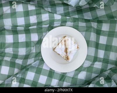 Vista dall'alto della torta "mille fogli" su una ceramica bianca piastra su fondo in tessuto scacchiato Foto Stock